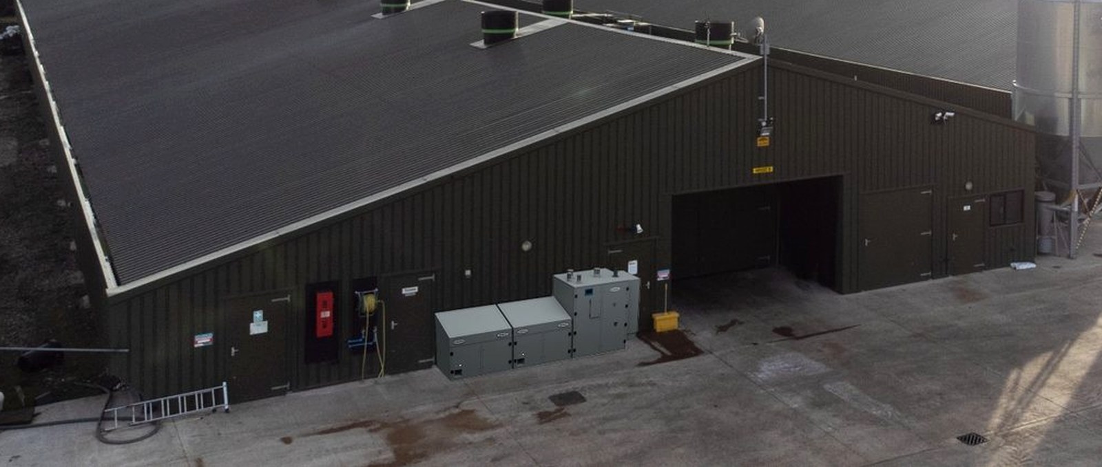 Two HERU units installed outside a working building, alongside existing plant